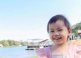 charmante petite fille asiatique de 3 ans souriant joyeusement à l'extérieur. photo