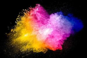 particule multicolore explosant sur fond noir. éclaboussures de poussière colorées. photo