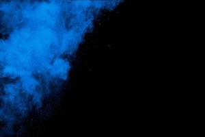 formes bizarres de nuage d'explosion de poudre bleue sur fond blanc. éclaboussures de particules de poussière bleue lancées. photo