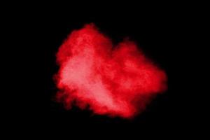 explosion de poudre de couleur rouge sur fond noir. mouvement de gel des éclaboussures de particules de poussière rouge. photo