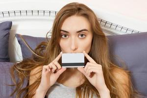 belle femme avec une carte de crédit sur un lit dans sa chambre photo