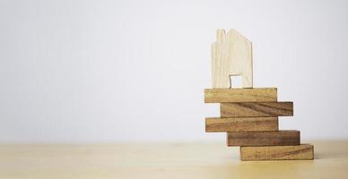 modèle de maison en bois posé sur le bord d'un empilement en bois pour la gestion des actifs à risque et l'assurance du concept immobilier. photo