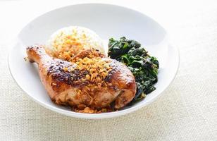 pilon de poulet mariné avec sauce chili épicée et herbes, servi avec riz cuit et épinards. photo