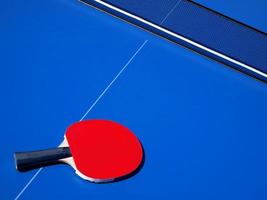 table de tennis bleue et batte de ping-pong rouge