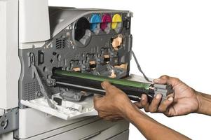 La main du technicien insère le tambour du copieur couleur dans le processus de révision sur fond isolé photo
