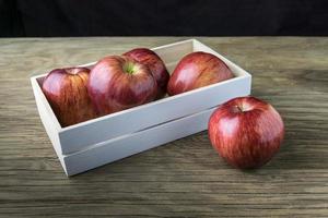 pommes dans la boîte. pommes rouges sur une table en bois. photo