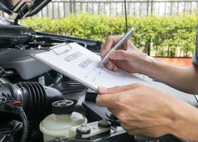 mécanicien inspectant la voiture endommagée et remplissant le formulaire de rapport d'accident photo