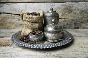 tasse d'argent et grains de café dans un sac en sac sur fond de bois photo