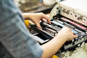 femmes tenant une cartouche de toner laser, remplaçant le toner dans une imprimante laser au bureau. concept de réparation et d'entretien des imprimantes laser photo