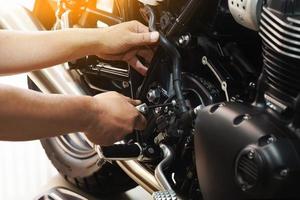 Mécanicien tenant une clé hexagonale travaillant sur une moto dans un garage de motos, concept d'entretien et de réparation de motos. mise au point sélective photo