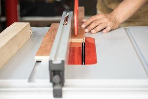 le charpentier utilise des bâtons poussoirs ou des blocs poussoirs sur la scie à table, les bâtons poussoirs contrôlent le bois, gardent les mains et les doigts à l'abri de la lame, concept de travail du bois. mise au point sélective photo