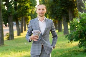 jeune homme d'affaires prospère montre de l'argent dans sa main. photo