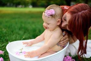 maman aide sa petite fille d'un an à se baigner dans la salle de bain. filmé dans un parc en pleine nature. photo