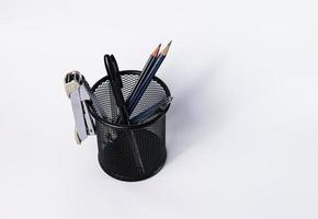 un petit panier noir en acier rond. peut être utilisé pour stocker des fournitures de bureau, y compris des stylos, des crayons, une agrafeuse, et avoir encore de la place pour mettre plus de choses. dans le fond blanc, il y a un espace de copie. photo