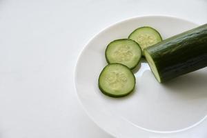 concombre entier et tranché sur une assiette blanche et une fourchette photo