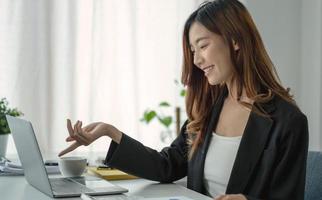 belle femme d'affaires asiatique analyse les graphiques à l'aide d'une calculatrice d'ordinateur portable au bureau. photo