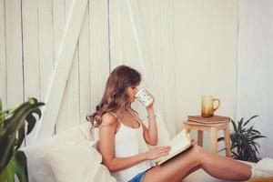 femme lisant un livre et buvant du thé photo