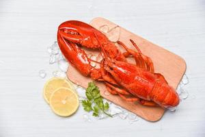 fruits de mer de homard avec de la glace sur une planche à découper en bois et de la coriandre citronnée - gros plan de nourriture de homard cuite à la vapeur photo