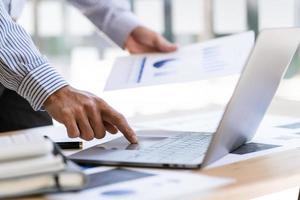 le directeur utilise un ordinateur portable tout en analysant les états financiers de l'entreprise à l'écran. photo