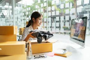 portrait jeune séduisante asie propriétaire femme démarrage entreprise travail heureux avec boîte à la maison préparer la livraison de colis dans la chaîne d'approvisionnement des PME, approvisionnement, concept de commerce en ligne omnicanal. photo