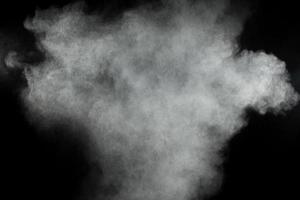 nuages d'explosion de poudre blanche. mouvement de gel des particules de poussière blanche sur fond noir. photo