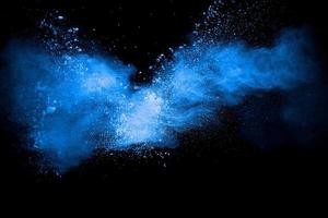 nuage d'explosion de poudre de couleur bleue sur fond noir. gros plan de particules de poussière bleue expirez. photo