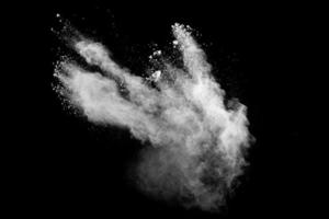 nuage d'explosion de poudre blanche sur fond noir. éclaboussures de particules de poussière blanche. photo