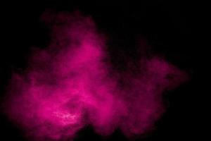éclaboussures de particules de poussière rose sur fond noir. éclaboussures de poudre rose. photo