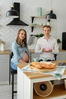 futur père avec sa femme enceinte tenant de petites chaussettes de bébé à côté de son