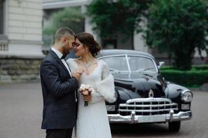 Heureux couple de mariage de luxe s'embrasser et s'embrasser près de rétro avec voiture bouquet en automne photo