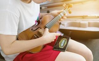 fille femme accorder son violon utiliser un téléphone électrique photo