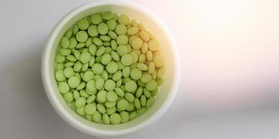 Comprimés ovales verts en pot blanc dans le concept de pharmacie de soins médicaux, fermé photo