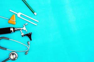 outils de médecin diapason, lampe de poche, coup de marteau, otoscope et stéthoscope sur fond de chirurgie verte avec espace de copie photo