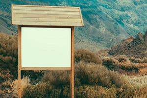 panneau d'affichage en bois avec panneau vierge dans un paysage de montagne photo