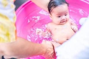 maman asiatique douche bébé pour nettoyer la saleté donner à l'enfant dans le bain récipient pour la propreté mode de vie famille entre mère et enfant utilisé pour la douche de bébé produits crème shampooings lotions et produits de soin pour bébé photo