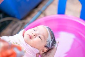 maman asiatique douche bébé pour nettoyer la saleté donner à l'enfant dans le bain récipient pour la propreté mode de vie famille entre mère et enfant utilisé pour la douche de bébé produits crème shampooings lotions et produits de soin pour bébé photo