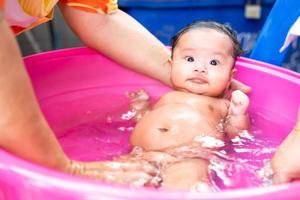 maman asiatique douche bébé pour nettoyer la saleté donner à l'enfant dans le bain récipient pour la propreté mode de vie famille entre mère et enfant utilisé pour la douche de bébé produits crème shampooings lotions et produits de soin pour bébé photo