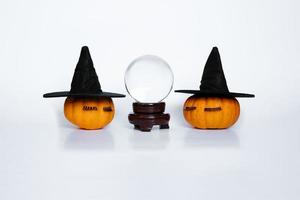 deux petites citrouilles avec des chapeaux et des cils de sorcière et une boule de cristal photo