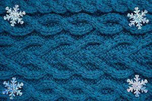 fond de pull en tricot bleu sarcelle avec des flocons de neige argentés dans les coins photo