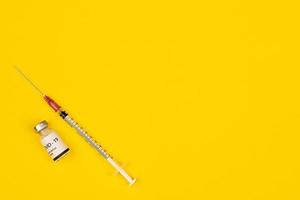 flacon de vaccin contre le coronavirus covid-19 et seringue mis sur fond jaune avec espace de copie. concept de propagation d'un remède contre l'épidémie de virus photo