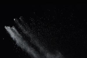 explosion de poudre blanche isolée sur fond noir. éclaboussure de particules de poussière blanche. photo