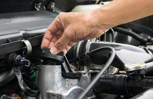 un mécanicien ouvre le bouchon d'huile d'un moteur de voiture. photo