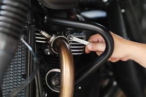 Mécanicien à l'aide d'une clé et d'une douille sur le tuyau d'échappement d'une moto. photo