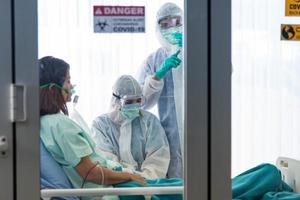 les médecins en tenue de protection vaccinent et surveillent la pression artérielle du patient infecté par corona visrus ou covid-19 dans la salle de quarantaine de l'hôpital. photo