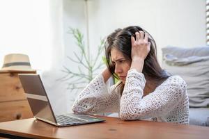 jeune femme avec ordinateur portable, employé de bureau fatigué et a mal à la tête. photo