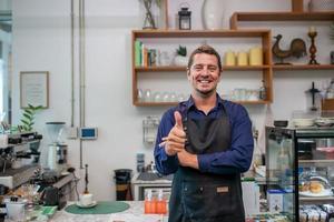 portrait d'un propriétaire souriant debout dans son café. propriétaire de café debout avec tablier dans un café pour accueillir le client. photo