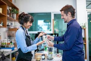 un barista heureux prend la commande avec une tablette du client dans un café. photo