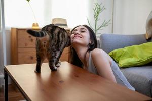 jeune femme jouant avec un chat sur le sol à la maison. photo