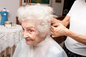 dame âgée se fait couper les cheveux dans le confort de sa maison photo