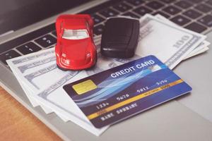 carte de crédit, modèle de voiture et cahier sur un bureau en bois. achats en ligne et paiement de voiture à l'aide d'un ordinateur portable photo